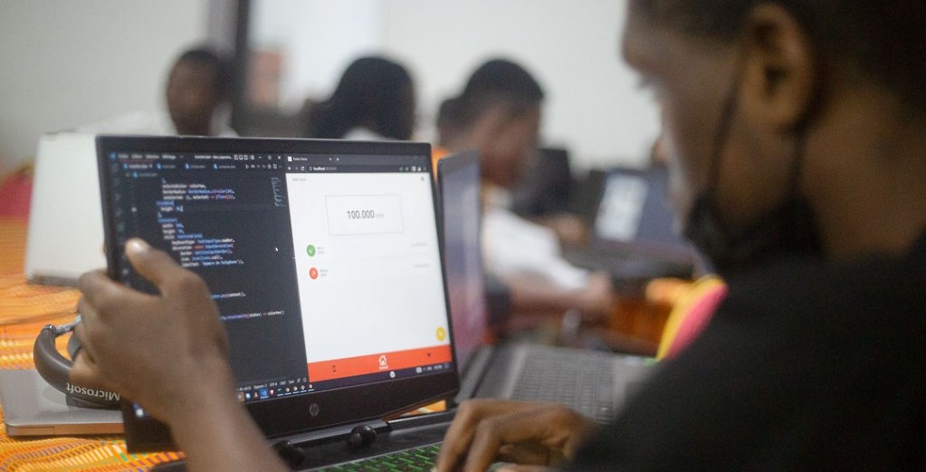 Un participant à un atelier utilisant un ordinateur portable pour gérer des finances scolaires, avec du code visible à l'écran.