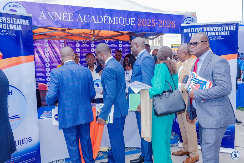 Un groupe de personnes interagissant autour d'un stand d'orientation académique lors d'un salon, avec des affiches et brochures sur les formations disponibles.
