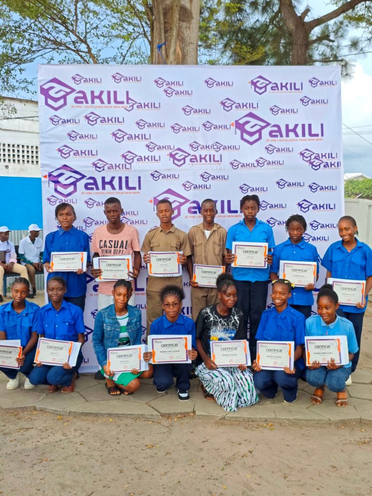 Groupe d'adolescents posant avec des certificats de réussite devant un fond portant le logo d'Akili.